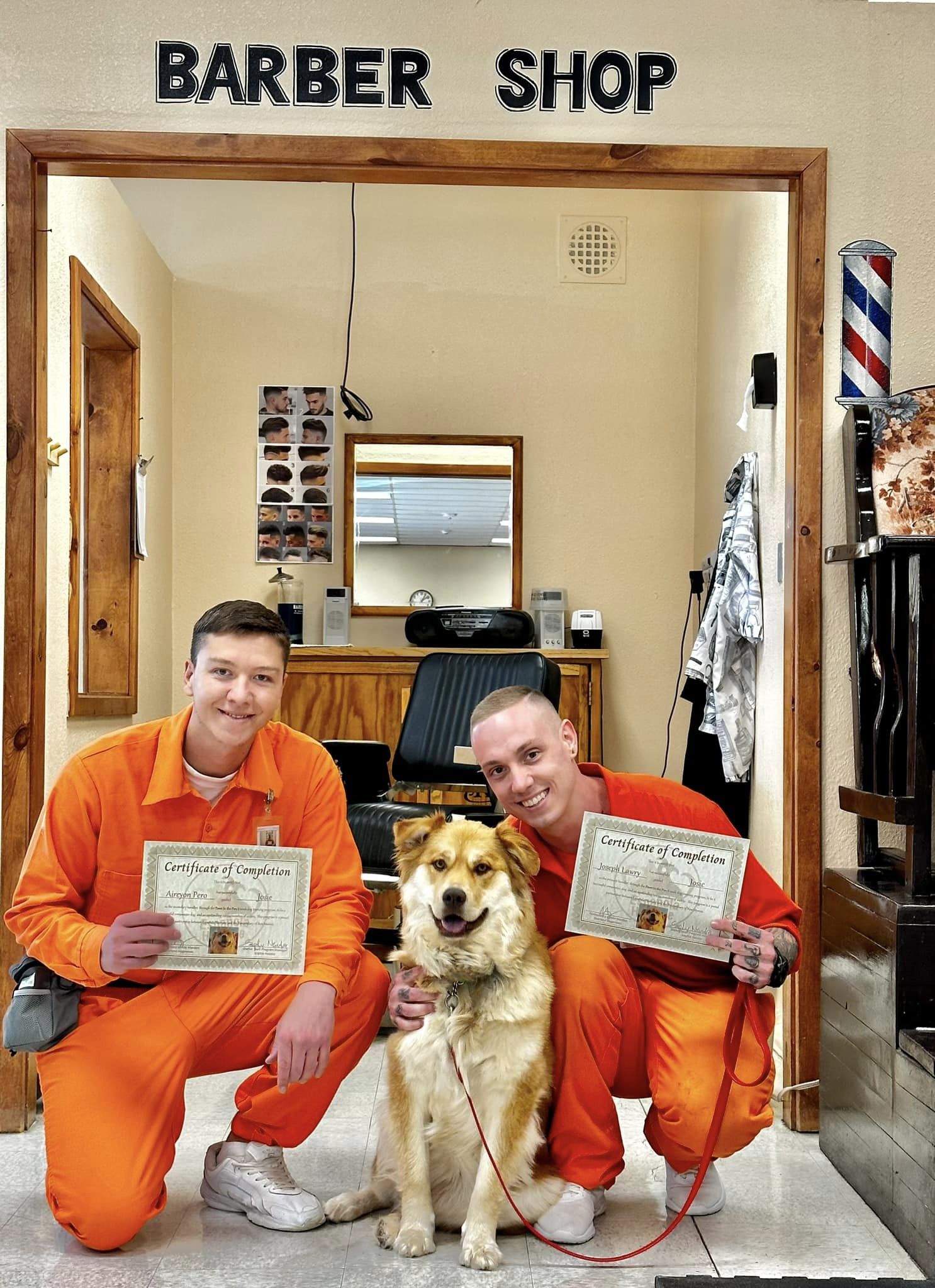 Inmates holding their certificates and petting a dog